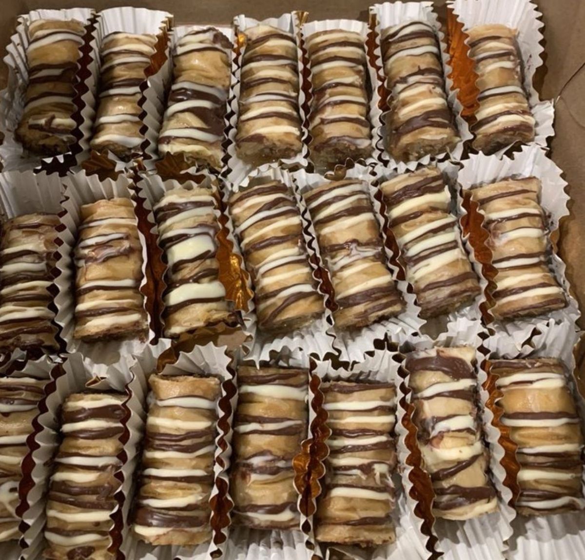 Cream-filled pastry rolls with chocolate and vanilla drizzle